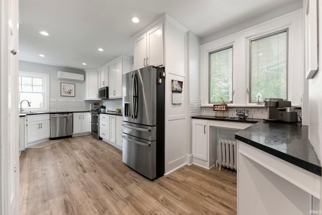 2215 Kensington Blvd, Fort Wayne, IN 46805 - kitchen featuring appliances with stainless steel finishes, radiator, a wall mounted AC, dark countertops, and light wood finished floors