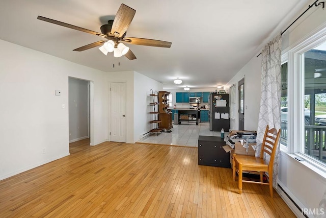 6659 W 400 S, Swayzee, IN 46986 - living room featuring baseboard heating, a ceiling fan, light wood-style floors, and baseboards