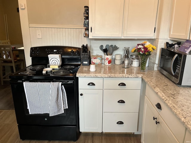 1746 College Ave, Huntington, IN 46750 - kitchen with electric range, stainless steel microwave, white cabinetry, tasteful backsplash, and wood finished floors