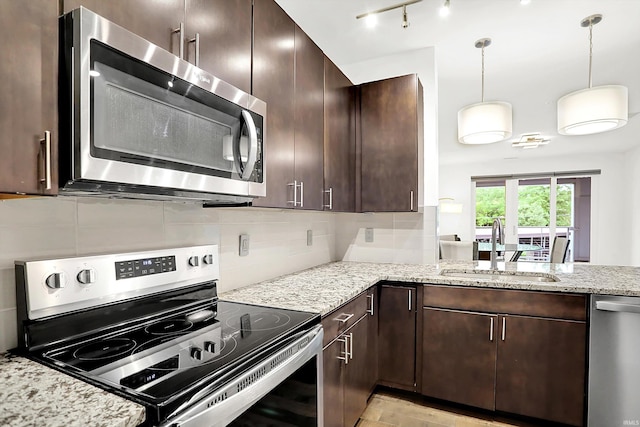 304 W Kirkwood Ave Unit 203, Bloomington, IN 47404 - kitchen featuring appliances with stainless steel finishes, a sink, dark brown cabinetry, light stone counters, and backsplash