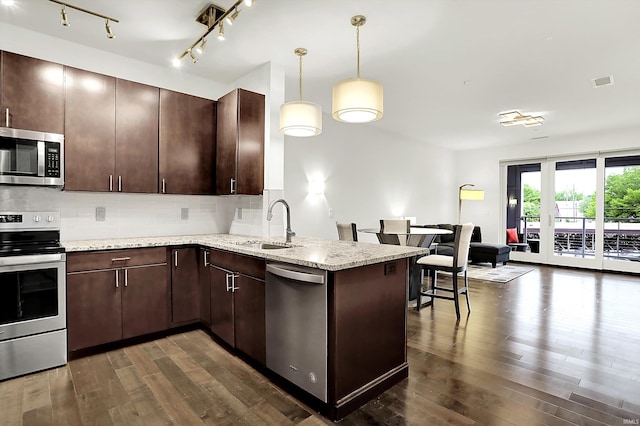 304 W Kirkwood Ave Unit 203, Bloomington, IN 47404 - kitchen featuring appliances with stainless steel finishes, dark wood-style flooring, a peninsula, backsplash, and a sink