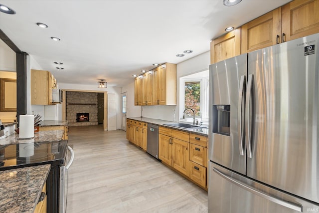16828 Barryknoll Way, Granger, IN 46530 - kitchen featuring stainless steel appliances, a warm lit fireplace, a sink, light wood finished floors, and recessed lighting