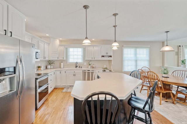 2006 Capital Hill Ct, Kokomo, IN 46902 - kitchen featuring stainless steel appliances, light wood-type flooring, a sink, white cabinets, and a kitchen bar