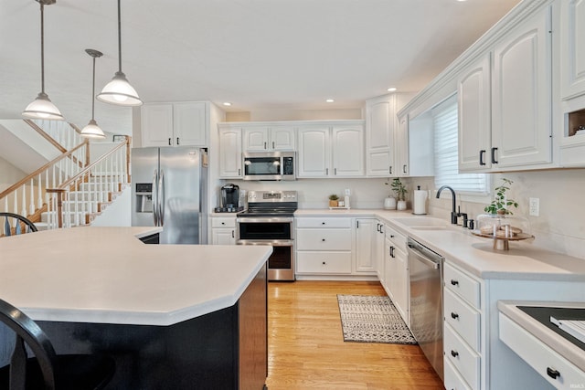 2006 Capital Hill Ct, Kokomo, IN 46902 - kitchen with appliances with stainless steel finishes, a sink, pendant lighting, light wood-style floors, and white cabinets