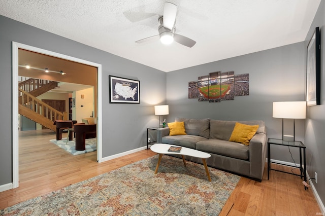 7301 W River Rd, Yorktown, IN 47396 - living room with stairs, wood finished floors, ceiling fan, baseboards, and a textured ceiling