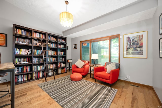 7301 W River Rd, Yorktown, IN 47396 - sitting room with a chandelier, wood finished floors, vaulted ceiling, baseboards, and bookshelves
