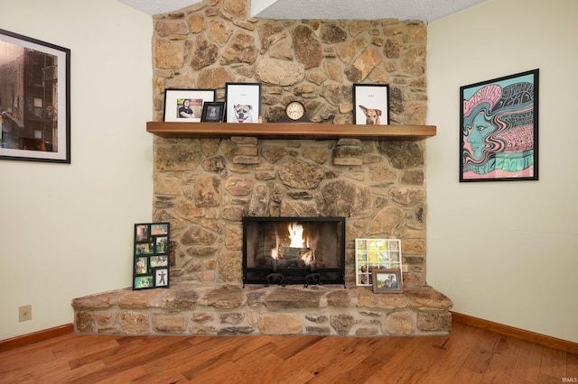 7301 W River Rd, Yorktown, IN 47396 - detailed view of baseboards, wood finished floors, a stone fireplace, and a textured ceiling