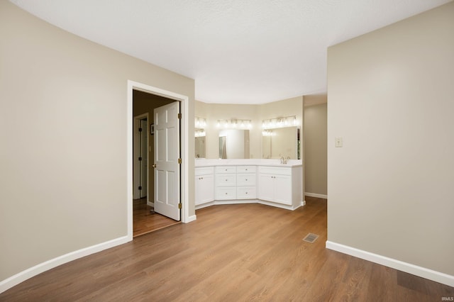 7301 W River Rd, Yorktown, IN 47396 - unfurnished bedroom featuring baseboards, light wood-style floors, ensuite bathroom, and a sink