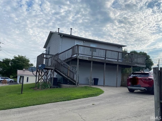 323 S John St, Bloomfield, IN 47424 - back of property with a deck, a lawn, stairway, and concrete driveway