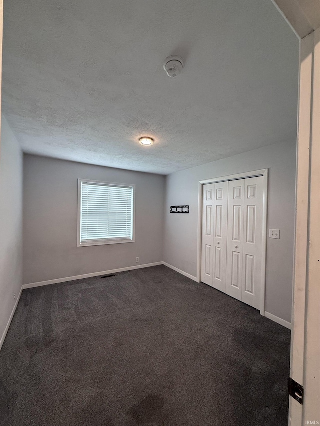 7540 S US-27 Hwy, Portland, IN 47371 - unfurnished bedroom with dark carpet, baseboards, a textured ceiling, and a closet