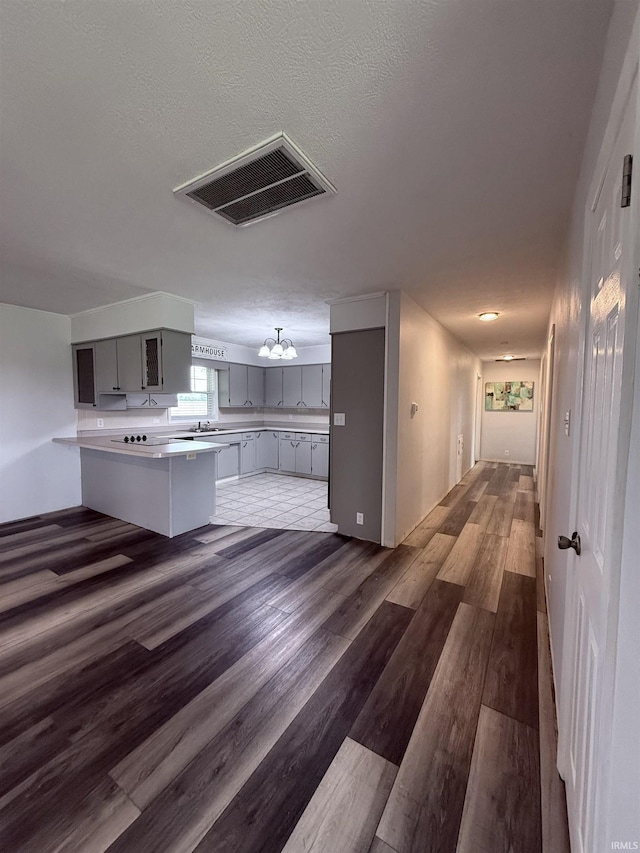 7540 S US-27 Hwy, Portland, IN 47371 - kitchen featuring gray cabinets, dark wood finished floors, light countertops, a peninsula, and a sink