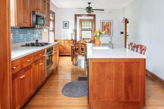 822 S Stull Ave, Bloomington, IN 47401 - kitchen with stainless steel appliances, a sink, light wood-type flooring, a kitchen island with sink, and a ceiling fan