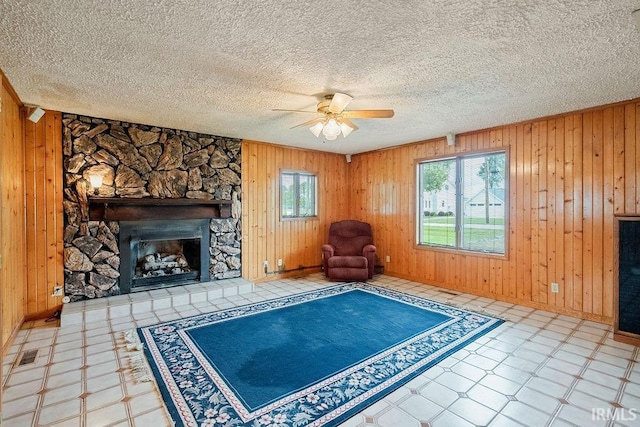 315 E Payton St, Greentown, IN 46936 - unfurnished room with a ceiling fan, wood walls, tile patterned floors, a stone fireplace, and baseboards