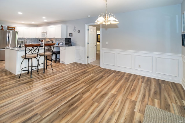 105 Temple Dr, Newburgh, IN 47630 - kitchen featuring a breakfast bar, stainless steel appliances, white cabinetry, light wood-style flooring, and wainscoting