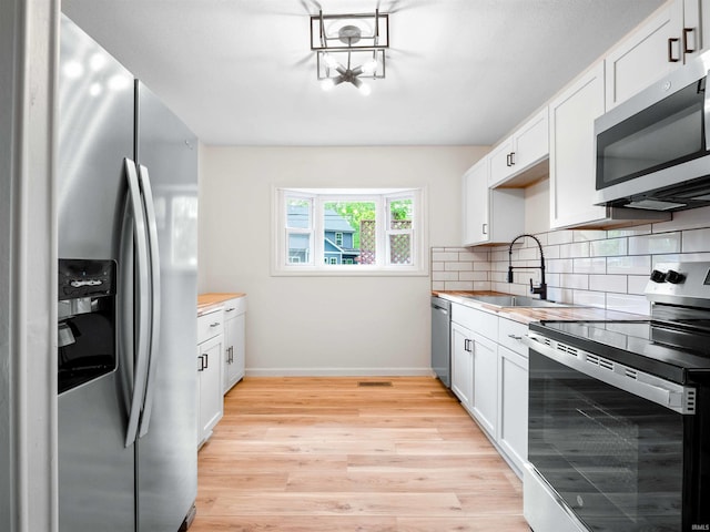 2834 Inwood Dr, Fort Wayne, IN 46815 - kitchen featuring appliances with stainless steel finishes, a sink, light wood-type flooring, tasteful backsplash, and baseboards