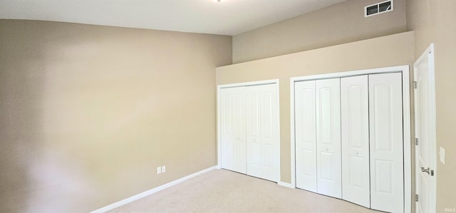1250 W Adams Hill Cir Unit 401, Bloomington, IN 47403 - unfurnished bedroom featuring two closets, light carpet, and baseboards