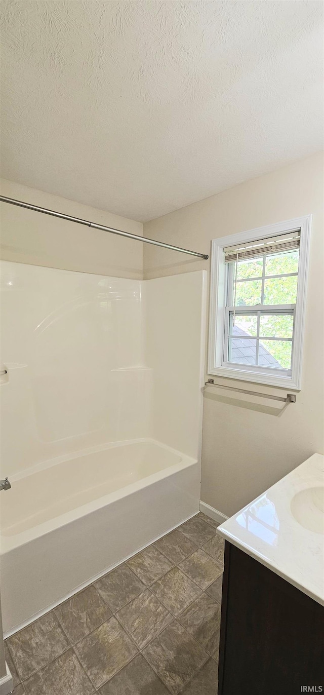 1250 W Adams Hill Cir Unit 401, Bloomington, IN 47403 - full bath with vanity, bathing tub / shower combination, a textured ceiling, stone finish floors, and baseboards