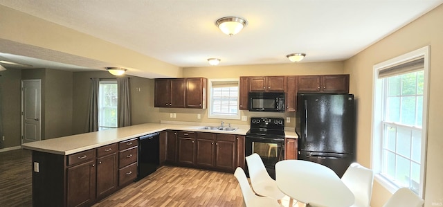 1250 W Adams Hill Cir Unit 401, Bloomington, IN 47403 - kitchen with black appliances, a sink, a peninsula, light countertops, and light wood-style flooring