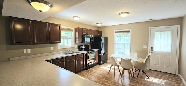 1250 W Adams Hill Cir Unit 401, Bloomington, IN 47403 - kitchen featuring black appliances, a sink, dark brown cabinetry, light wood-style flooring, and light countertops