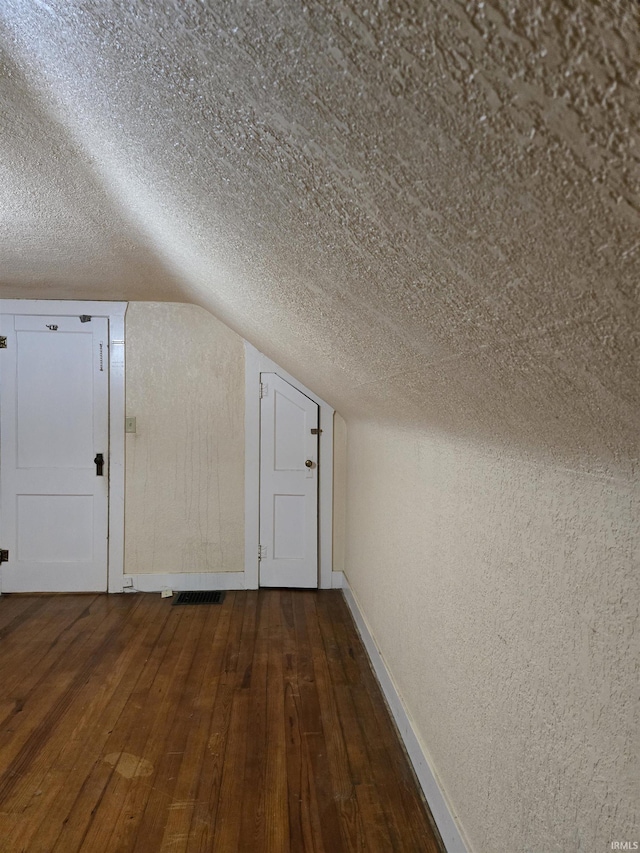 910 Ridgeway Ave, Vincennes, IN 47591 - additional living space with baseboards, lofted ceiling, dark wood-style flooring, a textured wall, and a textured ceiling