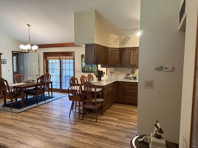 2807 Avondale Rd, Vincennes, IN 47591 - kitchen with light wood-type flooring, vaulted ceiling, light countertops, a chandelier, and dark brown cabinetry