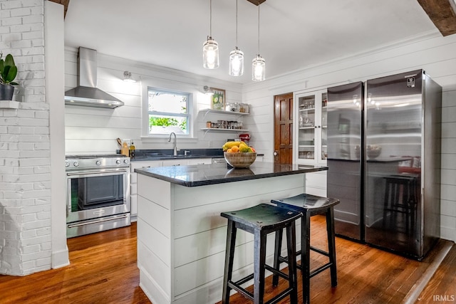 704 Avondale St, West Lafayette, IN 47906 - kitchen featuring appliances with stainless steel finishes, wall chimney range hood, dark wood-style floors, a breakfast bar area, and a kitchen island