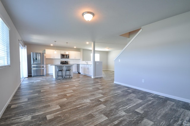 409 W Somerfield Dr, Lakeville, IN 46536 - unfurnished living room with dark wood-style floors, baseboards, and a sink