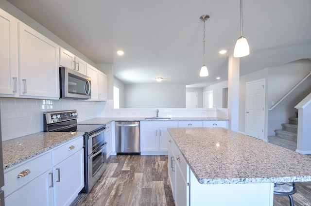 409 W Somerfield Dr, Lakeville, IN 46536 - kitchen featuring stainless steel appliances, a sink, dark wood-style flooring, white cabinetry, and a center island