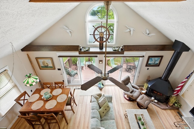 5585 S 930 E, Wolcottville, IN 46795 - living room with a textured ceiling, a wood stove, wood finished floors, plenty of natural light, and high vaulted ceiling