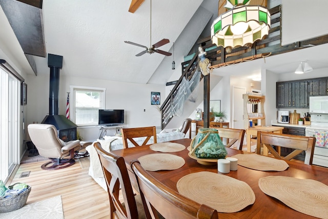 5585 S 930 E, Wolcottville, IN 46795 - dining room with a wood stove, ceiling fan, light wood-style flooring, stairway, and high vaulted ceiling