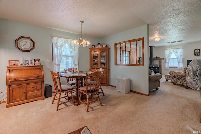11542 S 700 E, Lafontaine, IN 46940 - dining area featuring light colored carpet, a textured ceiling, a chandelier, a wood stove, and baseboards