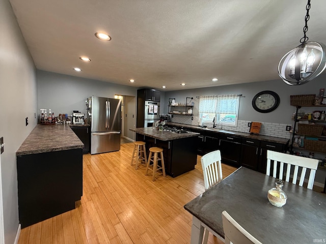 2782 W State Road 32nd Rd, Covington, IN 47932 - kitchen featuring stainless steel appliances, dark cabinetry, a kitchen island, a breakfast bar area, and decorative backsplash