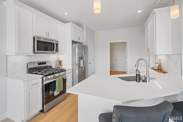 2487 Fiona Dr, Kokomo, IN 46902 - kitchen featuring stainless steel appliances, a sink, a peninsula, light wood-style floors, and white cabinets