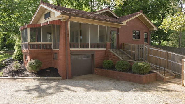 3601 Stringtown Rd, Evansville, IN 47711 - view of front of house with a sunroom, a garage, brick siding, and gravel driveway