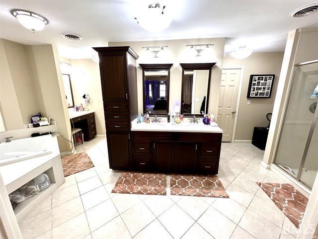 101 Hendron Hills Dr, Vincennes, IN 47591 - bathroom featuring two vanities, a stall shower, and tile patterned floors