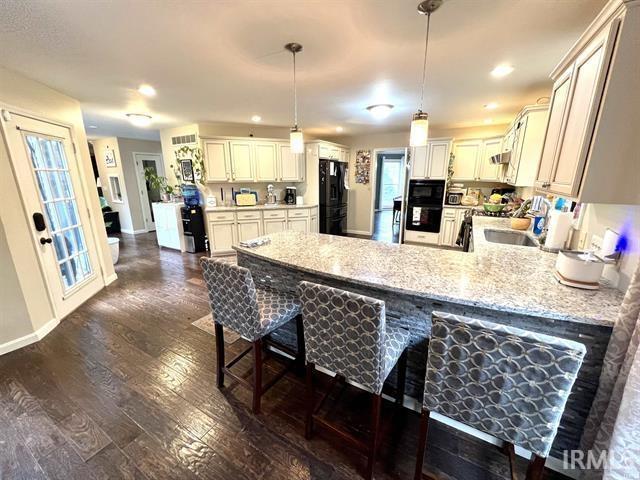 101 Hendron Hills Dr, Vincennes, IN 47591 - kitchen with black appliances, a peninsula, baseboards, dark wood-type flooring, and a breakfast bar