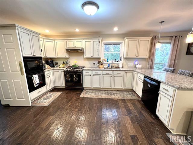 101 Hendron Hills Dr, Vincennes, IN 47591 - kitchen featuring black appliances, a peninsula, a sink, dark wood-style flooring, and light stone countertops