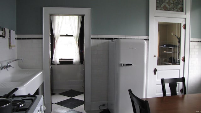 215 S Main St, Oakland City, IN 47660 - bathroom featuring tile walls, a sink, a wainscoted wall, and tile patterned floors