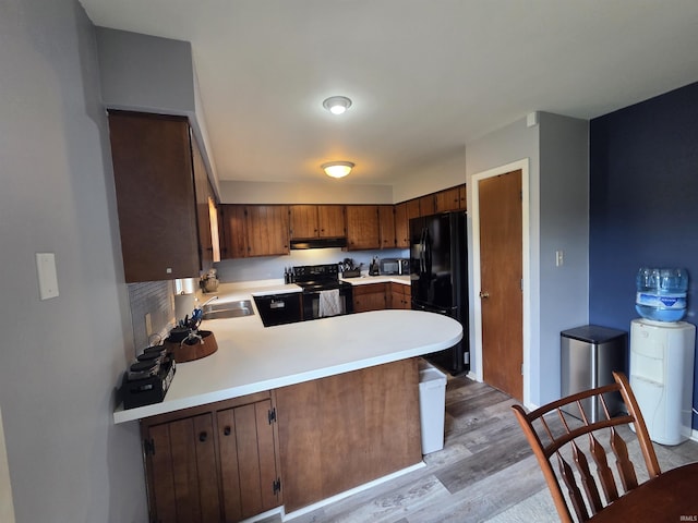 7823 Knightswood Dr, Fort Wayne, IN 46819 - kitchen featuring black appliances, light countertops, under cabinet range hood, light wood finished floors, and a peninsula