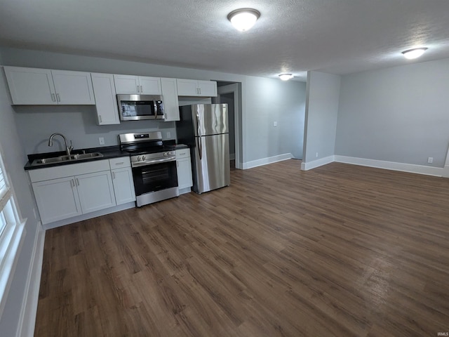 300 E Taylor St, Kokomo, IN 46901 - kitchen featuring stainless steel appliances, a sink, dark countertops, dark wood finished floors, and white cabinets