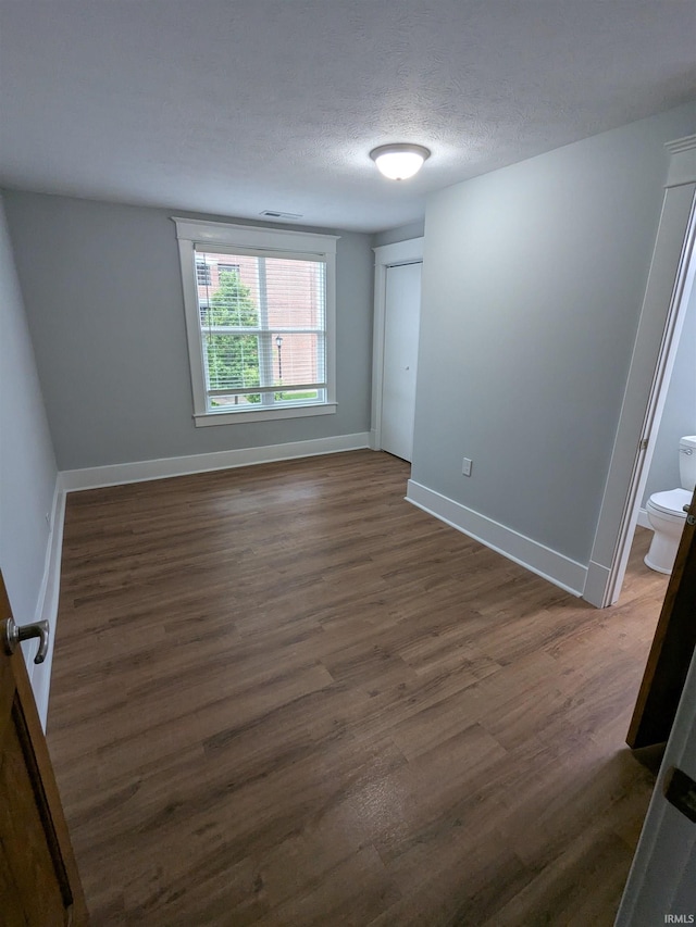 300 E Taylor St, Kokomo, IN 46901 - unfurnished room with dark wood-style floors, baseboards, and a textured ceiling