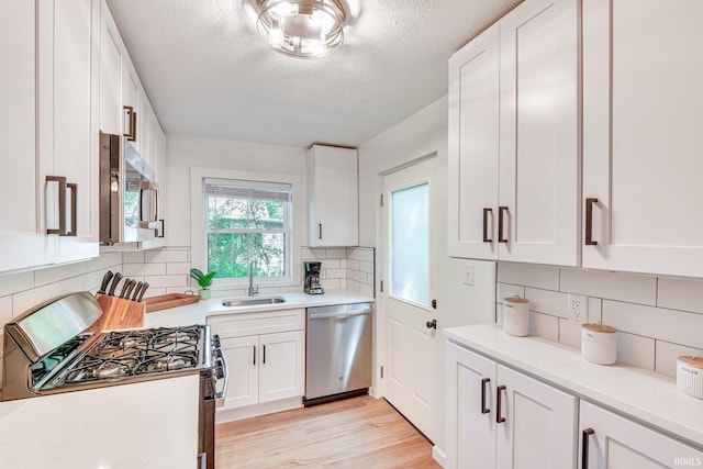 516 W Navarre St, South Bend, IN 46616 - kitchen with appliances with stainless steel finishes, a sink, backsplash, white cabinets, and a textured ceiling