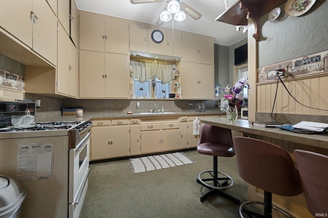 111 N State St, South Whitley, IN 46787 - kitchen featuring white range with gas cooktop, a ceiling fan, backsplash, light colored carpet, and cream cabinets