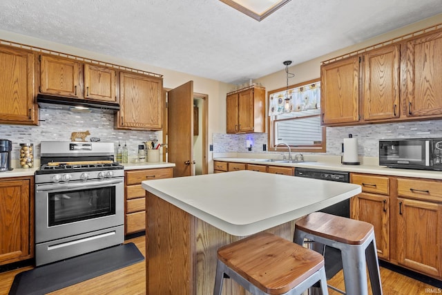 29900 Grant Rd, New Carlisle, IN 46552 - kitchen with stainless steel gas range oven, under cabinet range hood, black microwave, a textured ceiling, and a sink
