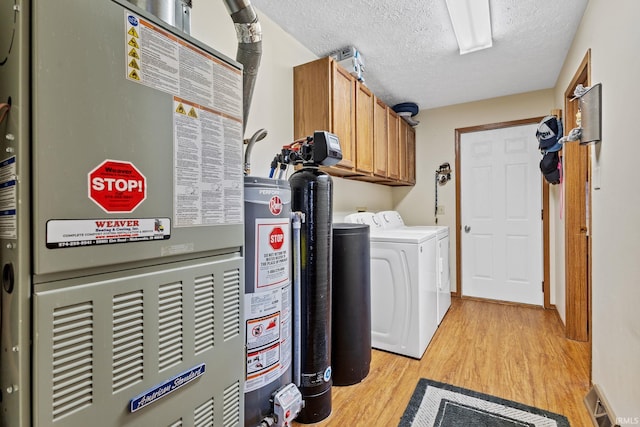 29900 Grant Rd, New Carlisle, IN 46552 - washroom featuring cabinet space, light wood-type flooring, washer and clothes dryer, heating unit, and a textured ceiling