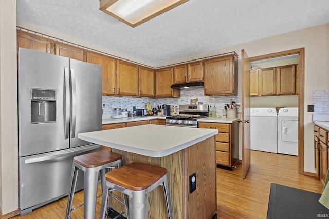 29900 Grant Rd, New Carlisle, IN 46552 - kitchen featuring stainless steel appliances, separate washer and dryer, under cabinet range hood, light wood finished floors, and a textured ceiling