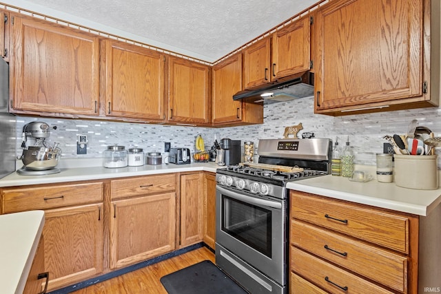 29900 Grant Rd, New Carlisle, IN 46552 - kitchen with stainless steel gas range oven, under cabinet range hood, light countertops, backsplash, and light wood-style floors