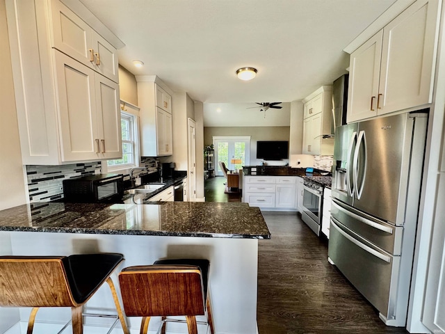 855 N Abigail Ln, Ellettsville, IN 47429 - kitchen with appliances with stainless steel finishes, a peninsula, a sink, white cabinets, and wall chimney exhaust hood