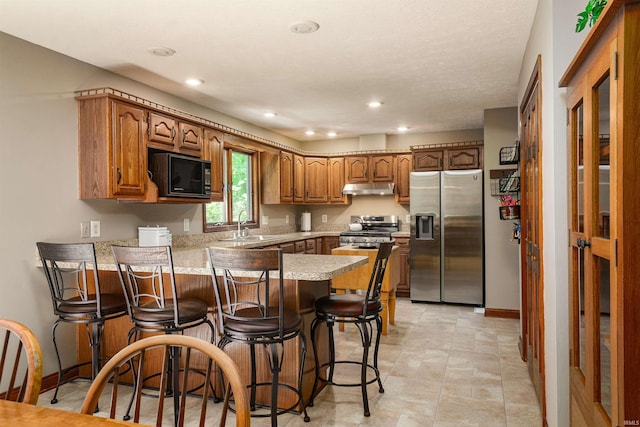 51410 Mansfield Dr, South Bend, IN 46628 - kitchen featuring appliances with stainless steel finishes, a peninsula, under cabinet range hood, light countertops, and brown cabinets