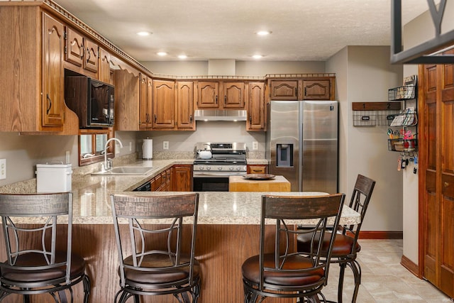 51410 Mansfield Dr, South Bend, IN 46628 - kitchen with appliances with stainless steel finishes, under cabinet range hood, a sink, a peninsula, and light countertops